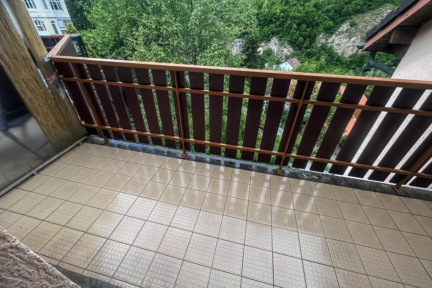 Balcon carrelé lavé, garde-corps bois et vue sur la vallée