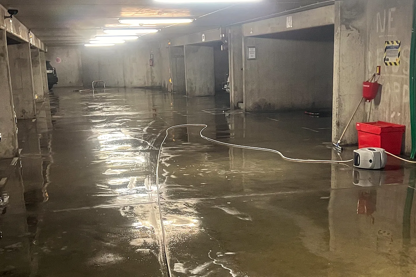 Parking souterrain en cours de lavage haute pression, sol encore inondé